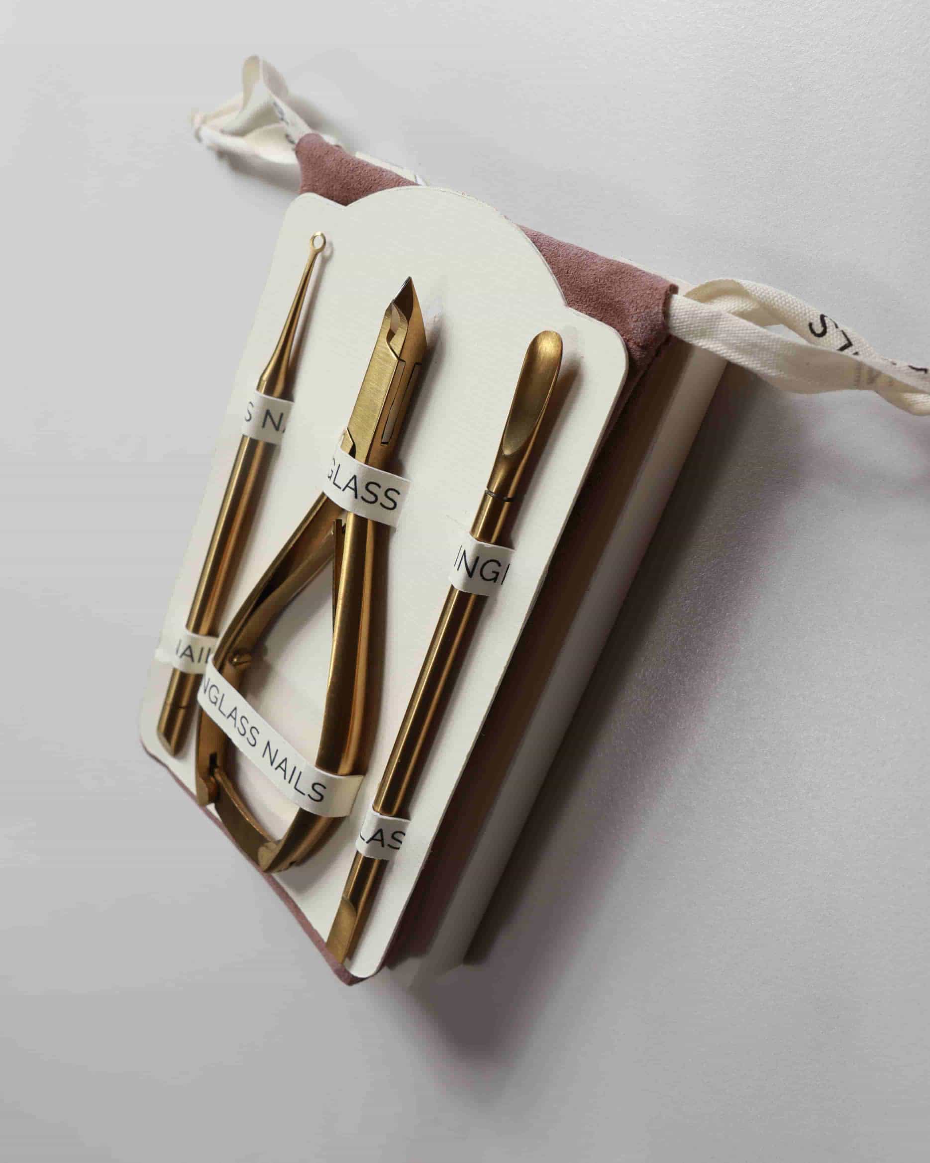 Set of gold nail tools in a white case on a light gray background