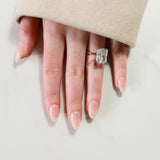 Hand wearing a diamond ring on a neutral background