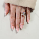 Hand wearing a diamond ring on a neutral background
