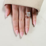 Hand wearing a diamond ring on a neutral background