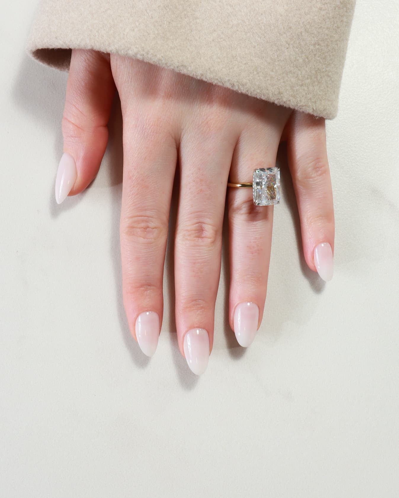 Hand wearing a diamond ring on a light background