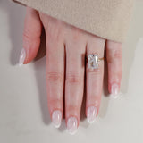 Hand wearing a diamond ring on a neutral background