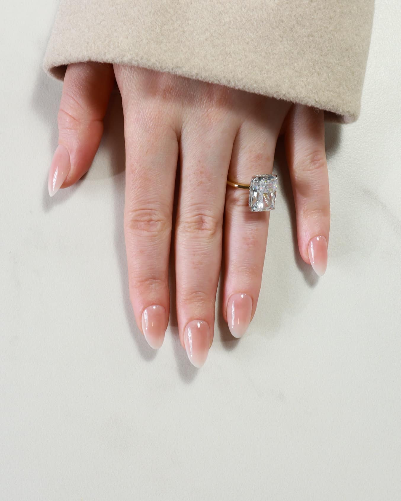 Hand wearing a diamond ring on a light background