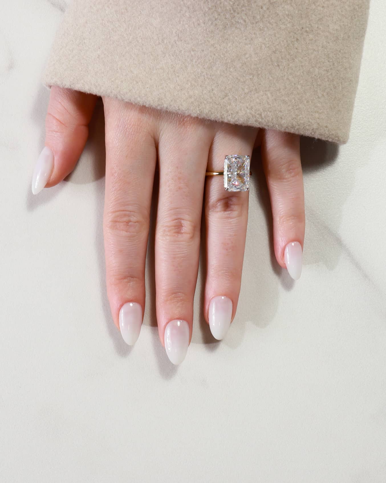 Hand wearing a diamond ring on a light background