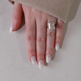 Hand wearing a diamond ring on a neutral background with shade in1 ombre