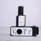 Black nail polish bottle with white label on a matching black and white stand against a light gray background