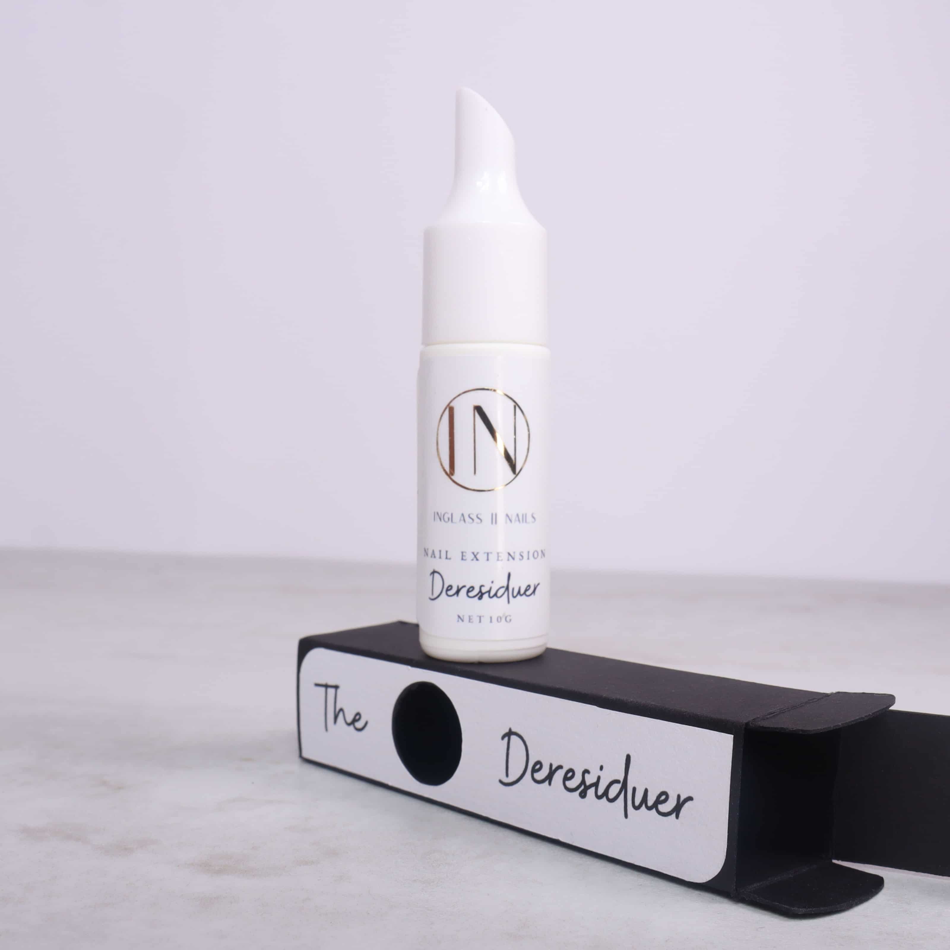 White bottle labeled 'IN' on a black stand with 'The Deresiduer' text against a light gray background