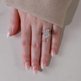 Hand wearing a diamond ring on a neutral background with shade in02