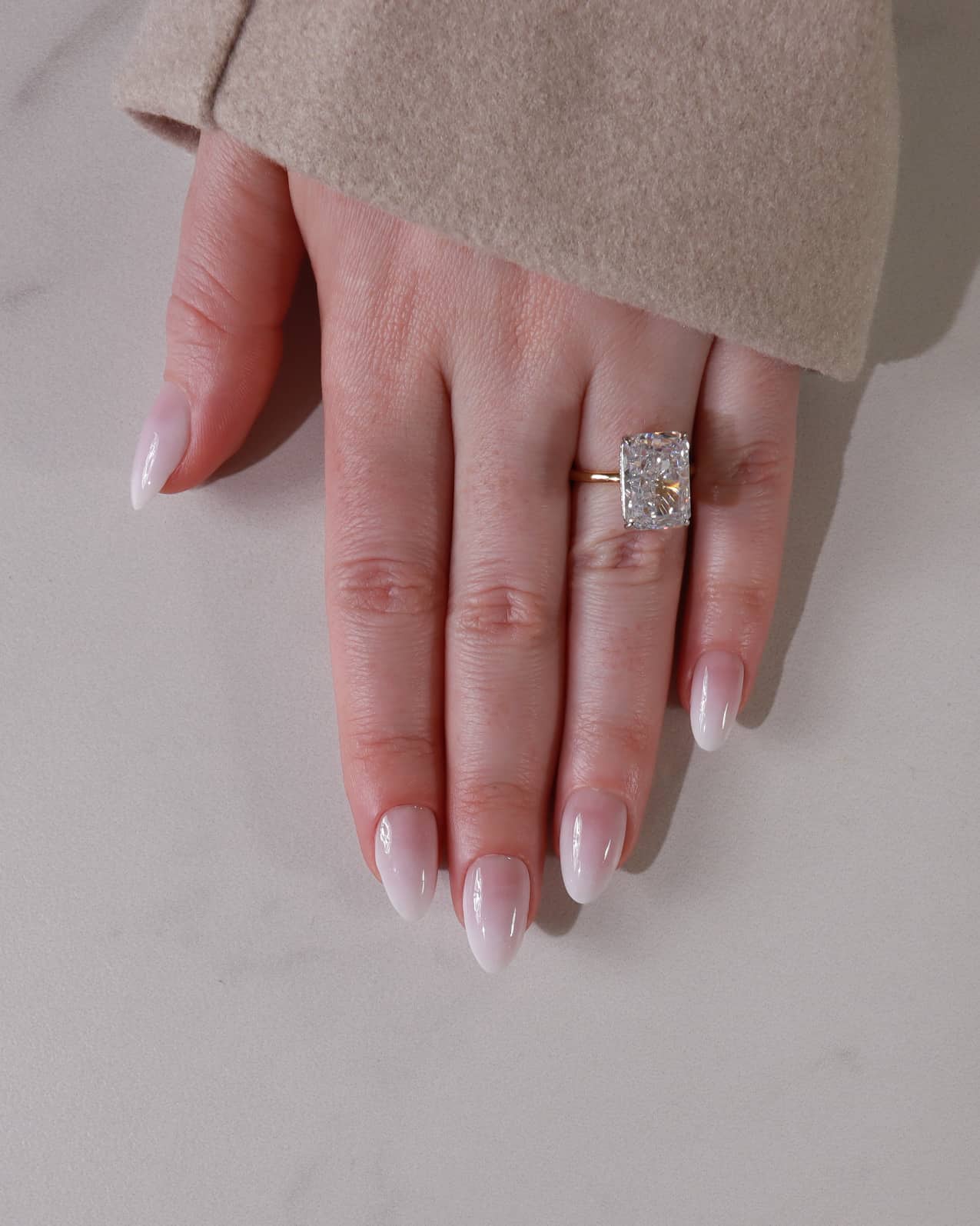 Hand wearing a diamond ring on a neutral background with shade in04