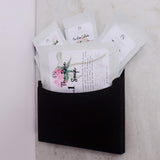 Black pouch with manicure and pedicure spa kit on a light marble background